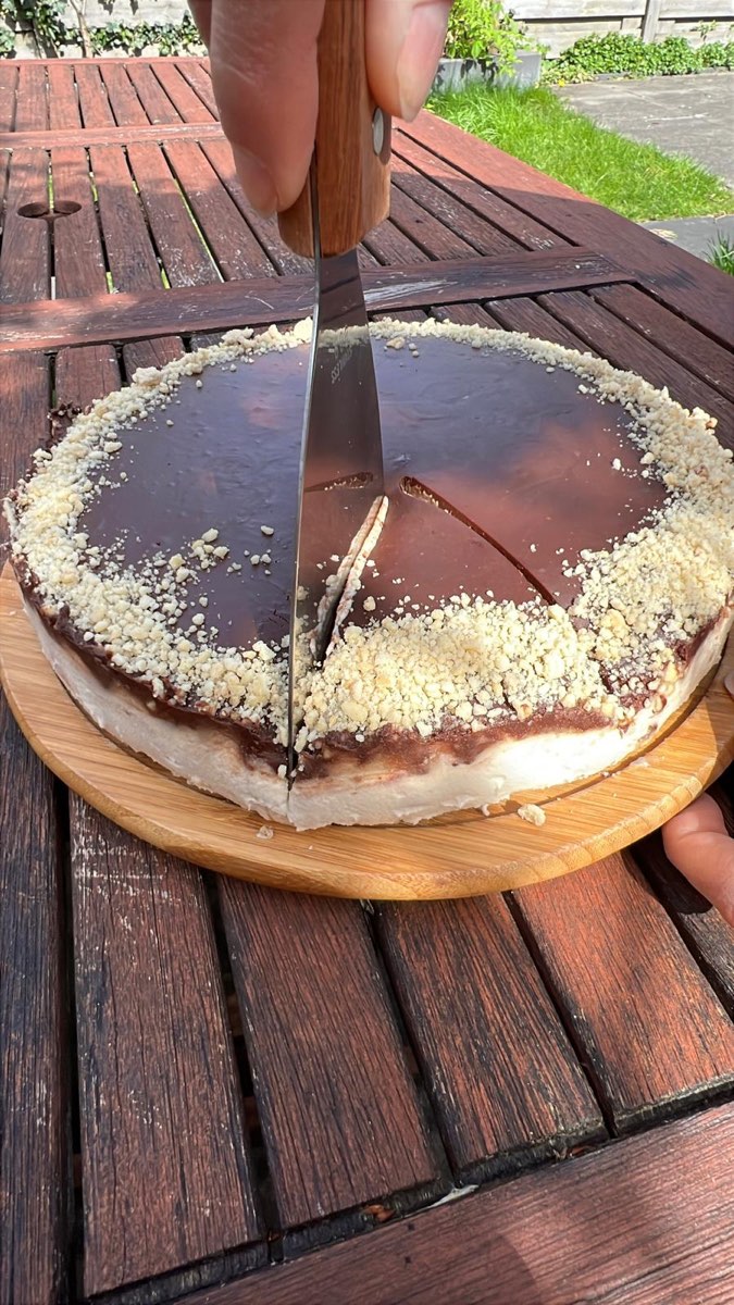 Vegan verjaardagscheesecake met pure chocolade ganache wordt aangesneden