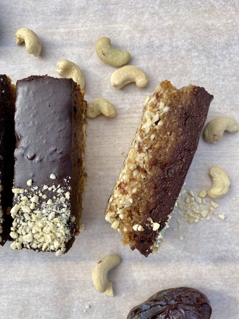 Doorsnede van een vegan snickers cheesecake reep met dadelkaramel-pindavulling